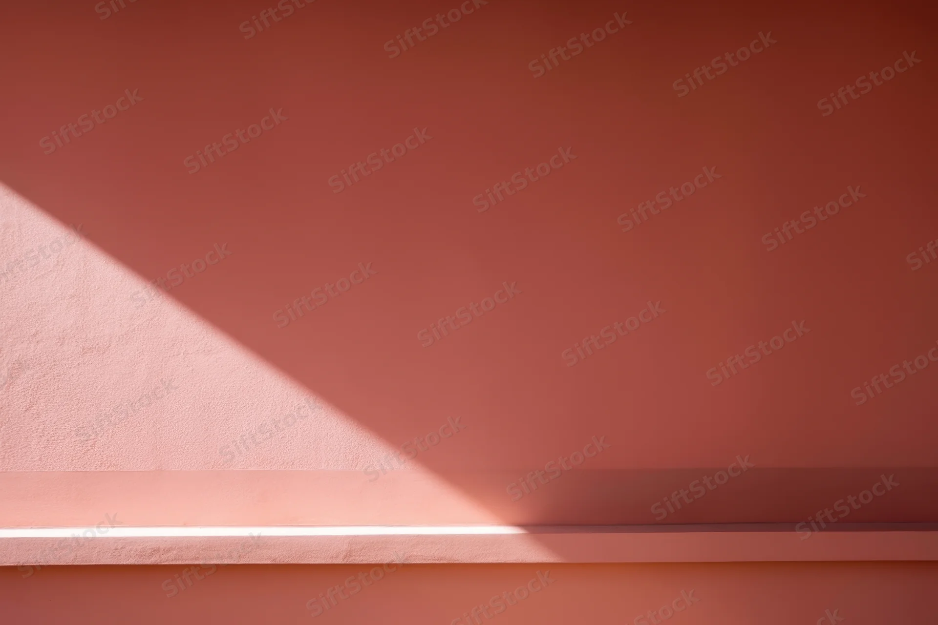 Diagonal beam of light casting shadow on warm pink wall in minimalist interior
