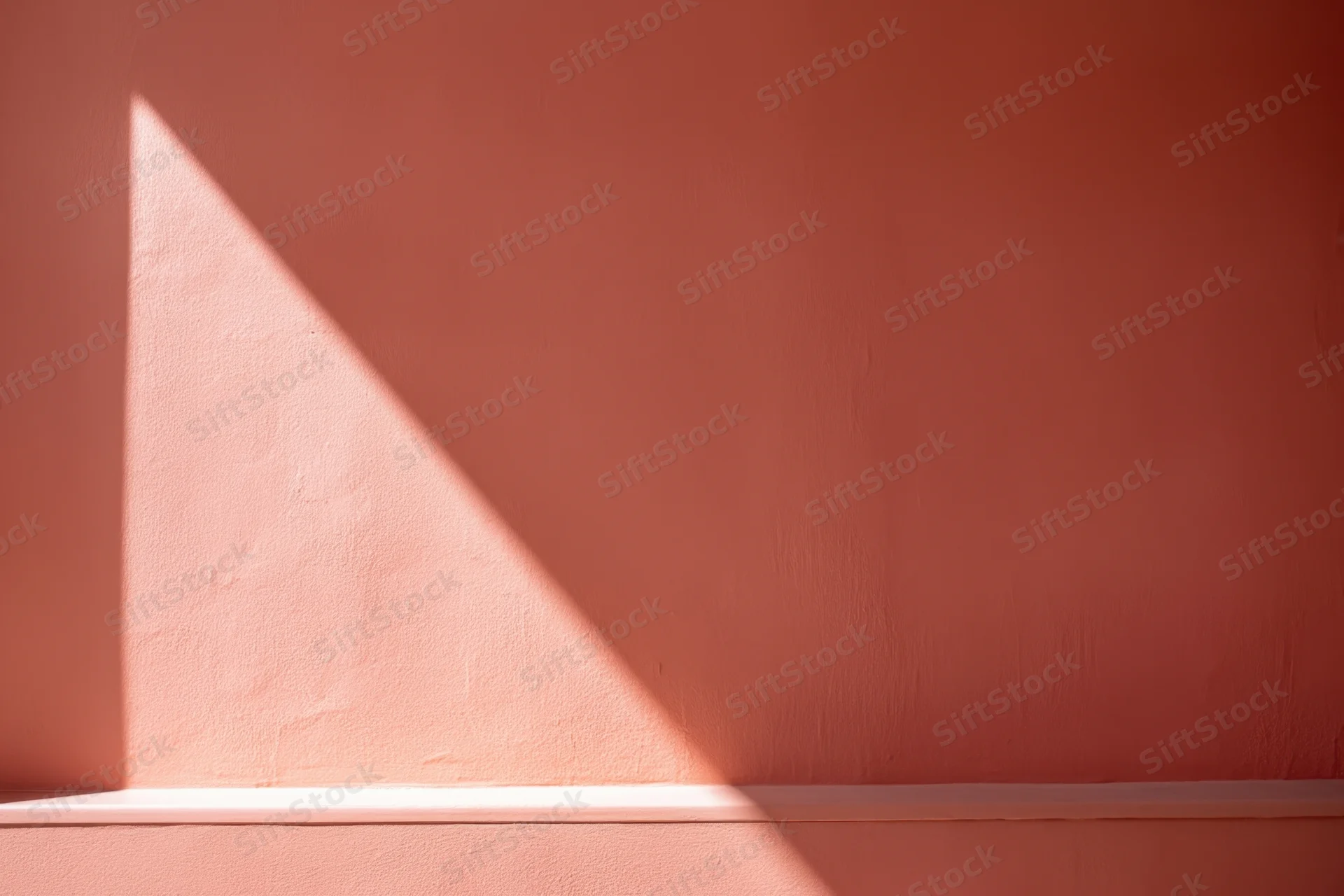 Diagonal sunlight beam on warm pink interior wall