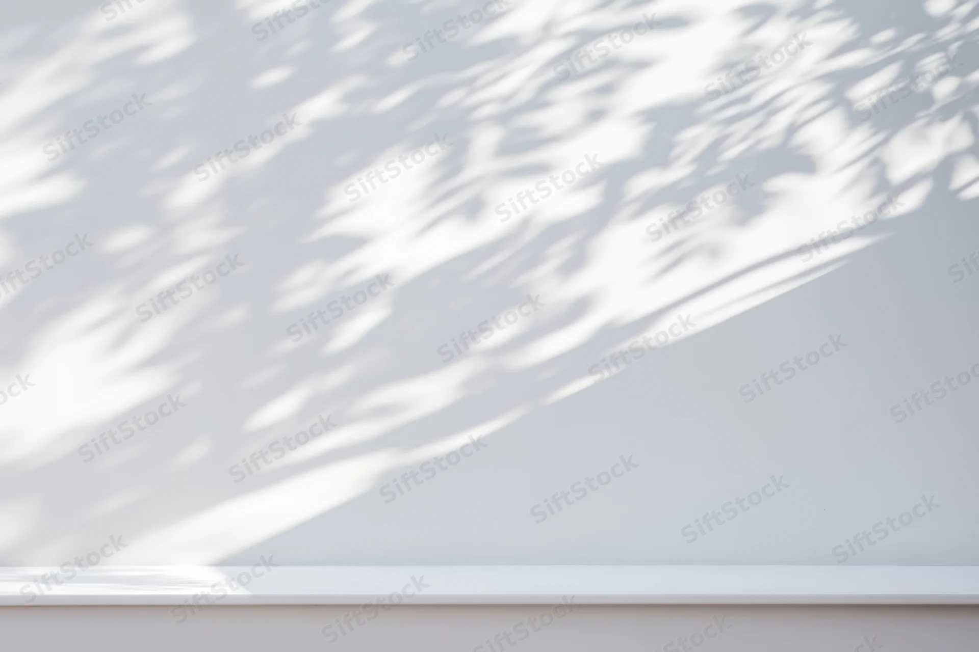 Dappled sunlight casts soft tree shadows on a smooth white wall in a minimalist interior