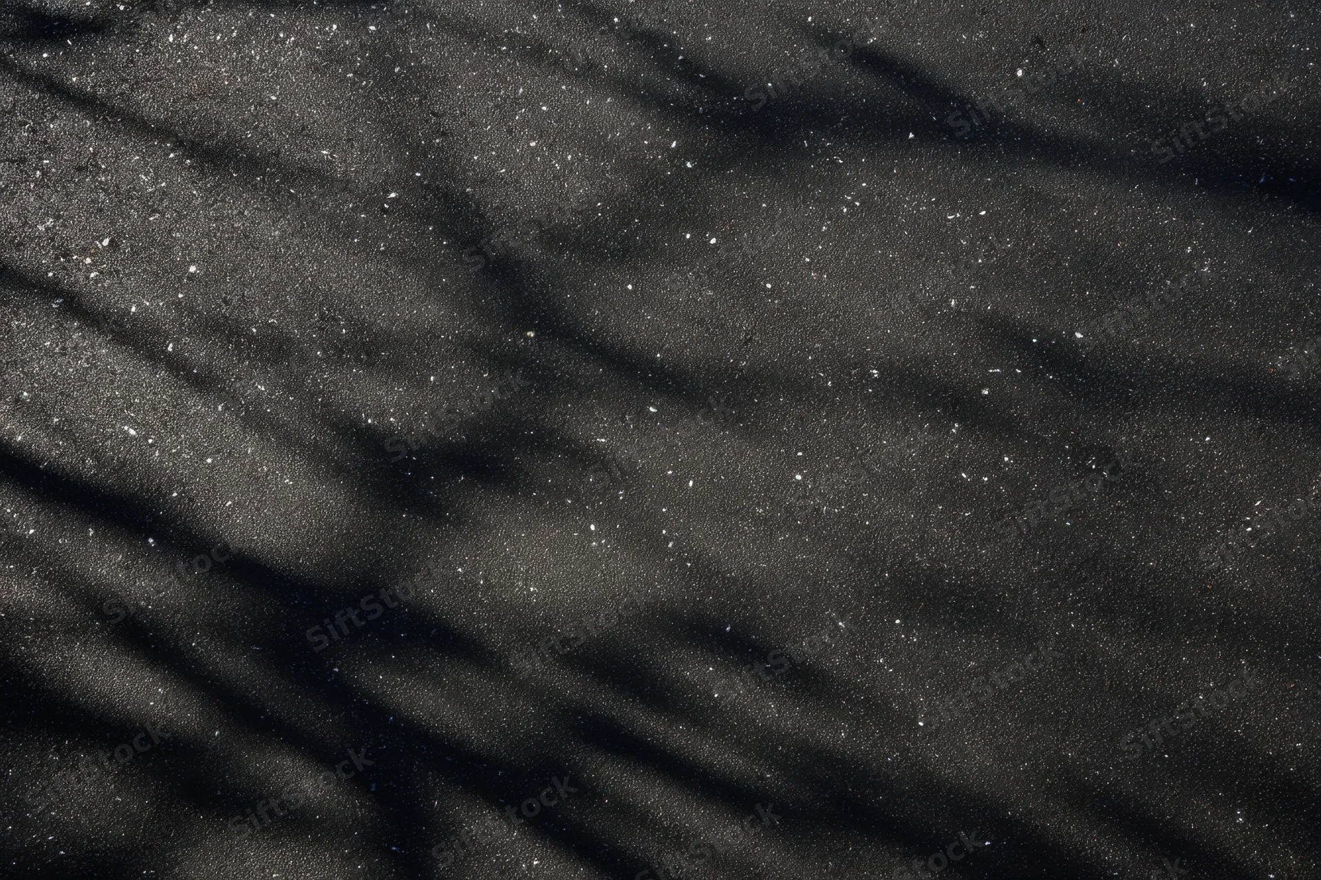 Dark textured black wall with speckled highlights and wrinkled surface