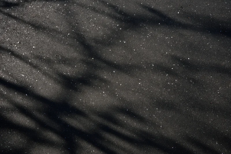 Dark textured black wall with speckled highlights and wrinkled surface