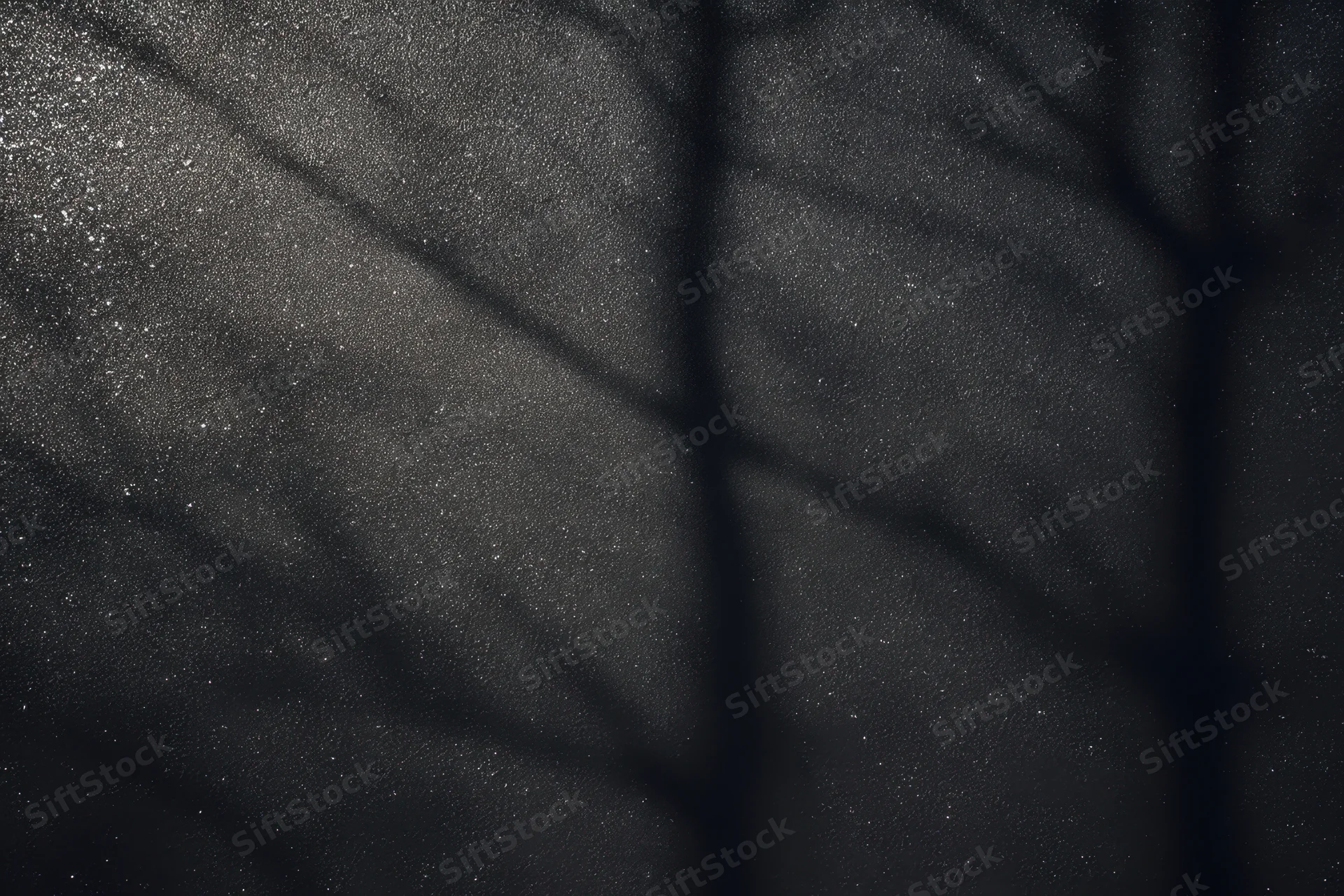Dark textured wall with speckled highlights and shadow patterns