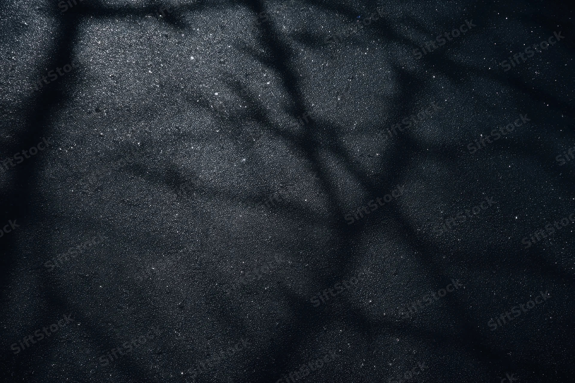 Dark grunge-textured wall with speckled highlights and cracked surface