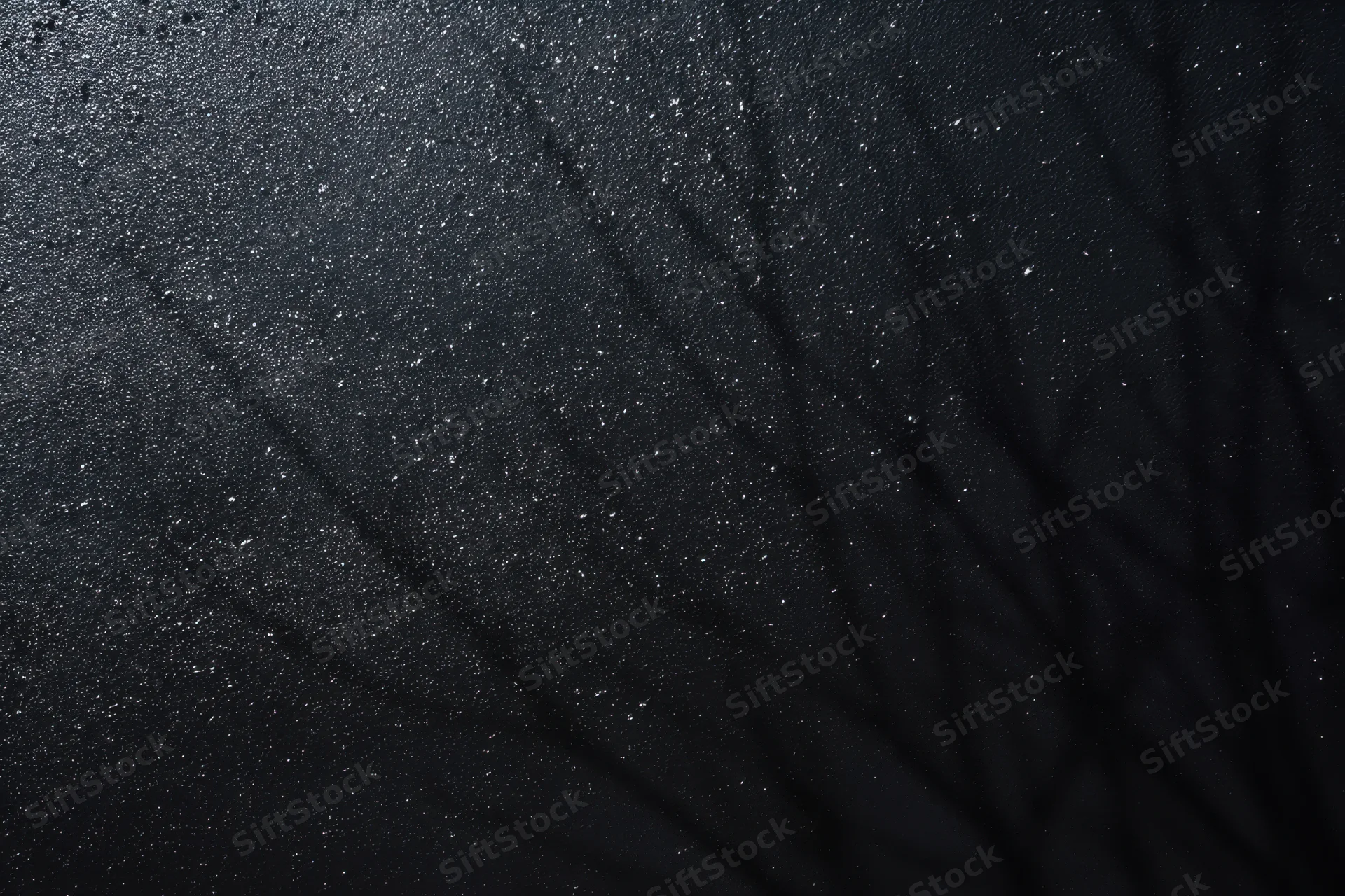 Dark grunge-textured wall with speckled highlights and shadowed surface