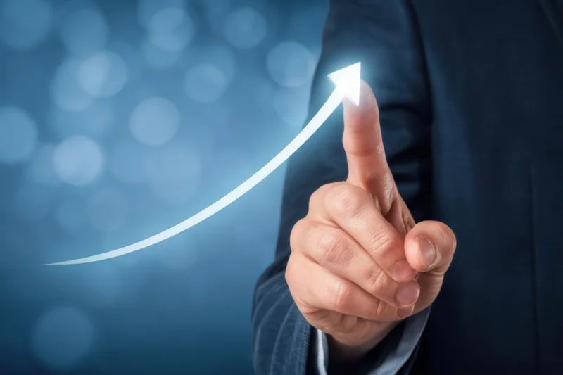 Businessman pointing at glowing upward arrow on digital interface