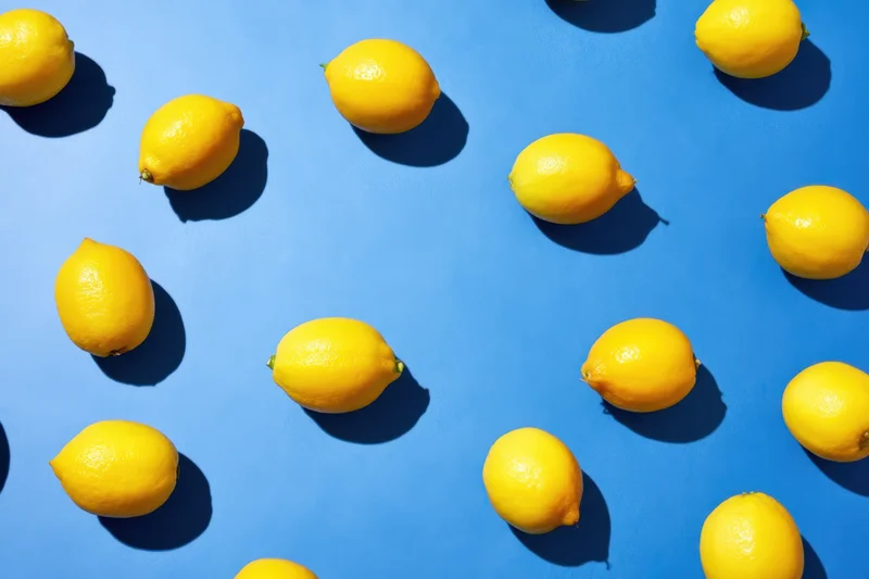 Lemons arranged in a repeating pattern on a blue surface viewed from above