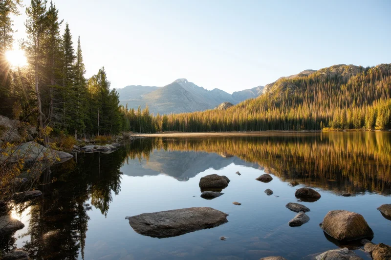 Alpine lake reflecting golden autumn forest and mountains at sunset