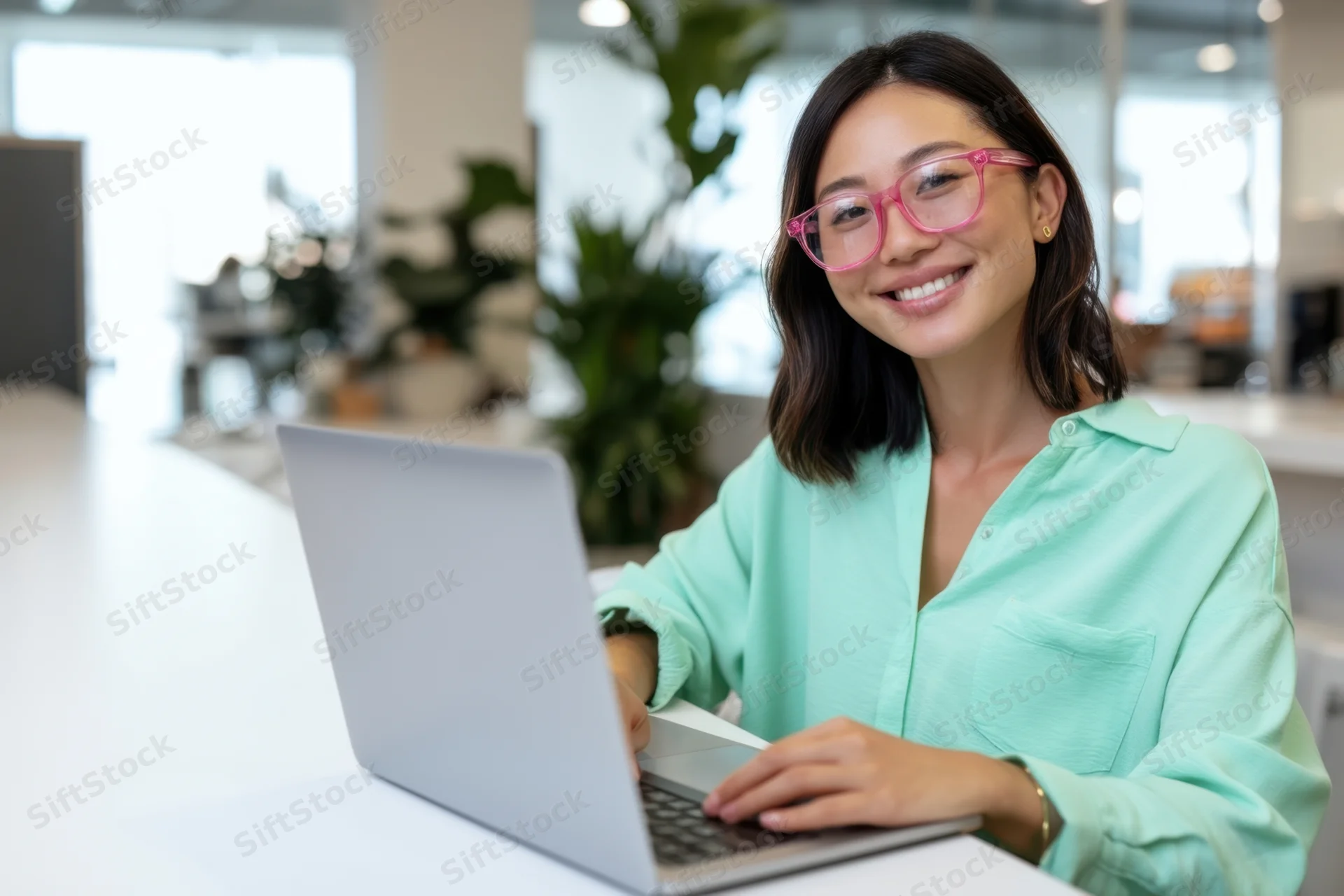 Smiling asian woman using laptop at office desk