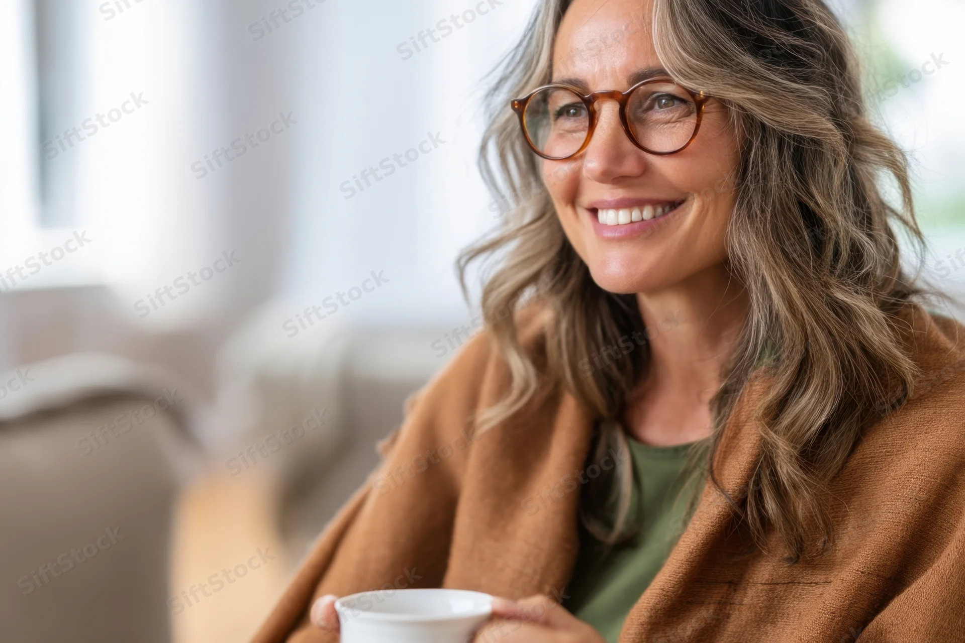 Woman smiling while holding a white coffee cup indoors