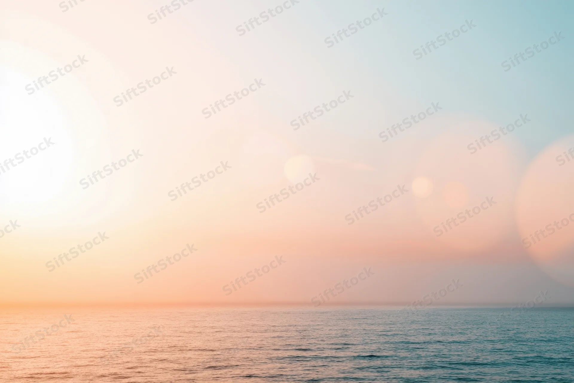 Soft sunset over calm ocean with pastel sky and hazy horizon