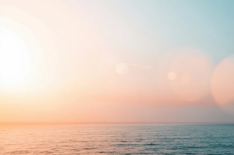 Soft sunset over calm ocean with pastel sky and hazy horizon