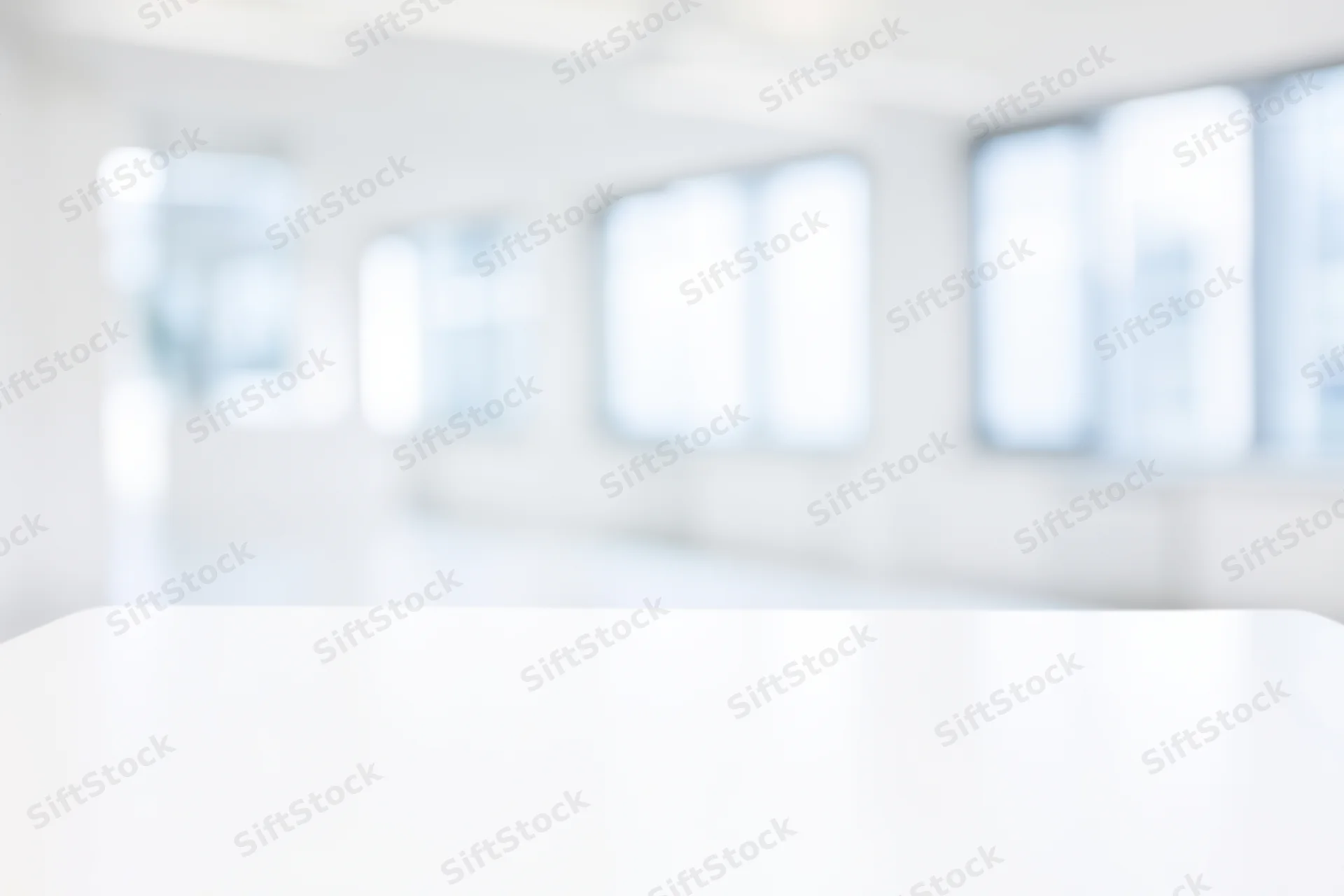White table in a bright modern studio interior with blurred background
