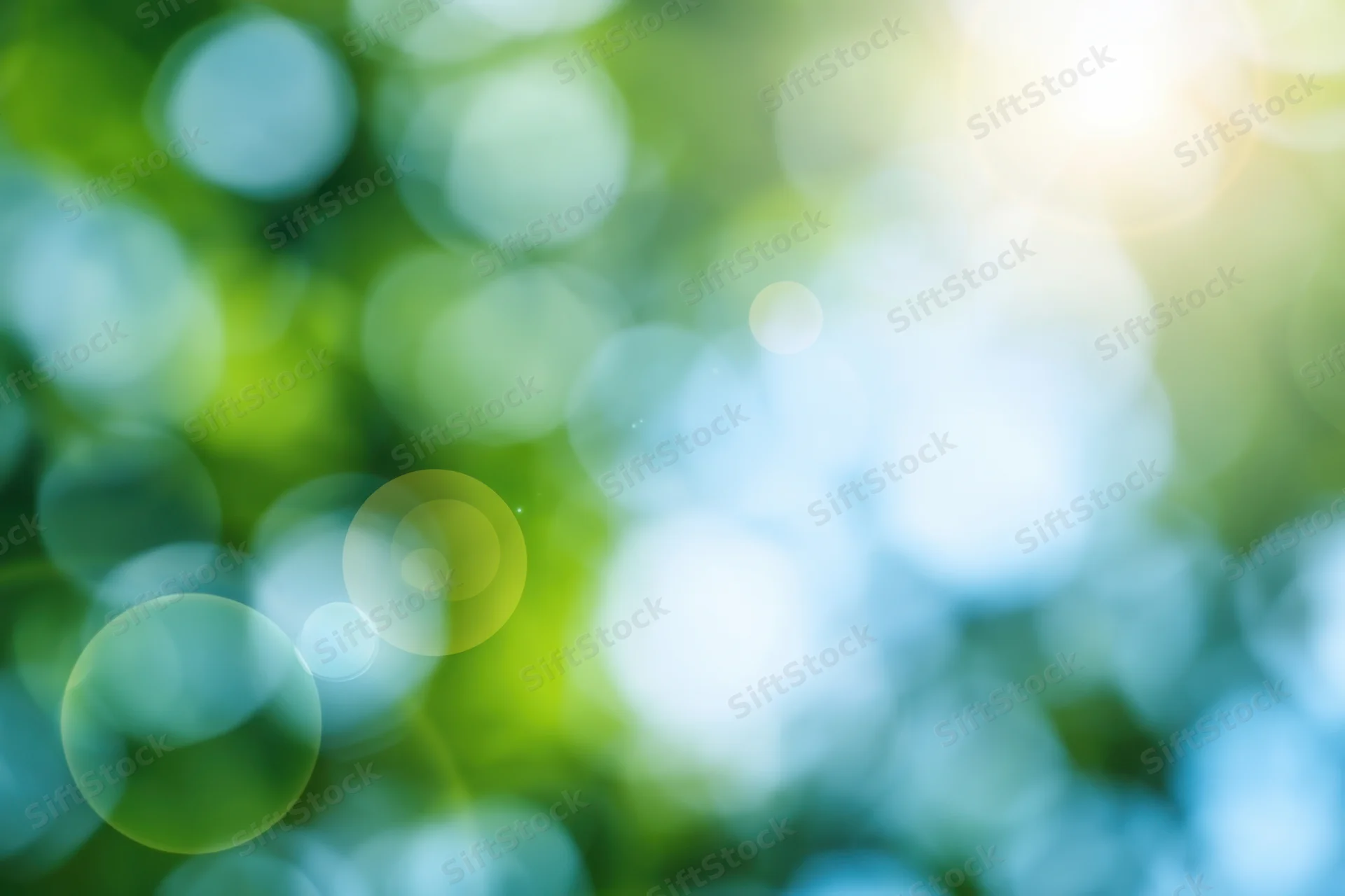 Abstract nature background with soft green and blue bokeh from sunlight filtering through foliage