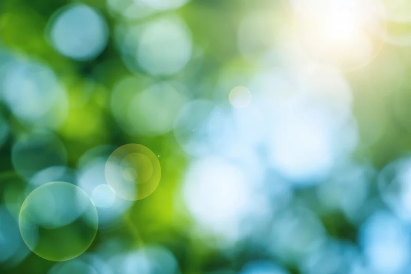 Abstract nature background with soft green and blue bokeh from sunlight filtering through foliage