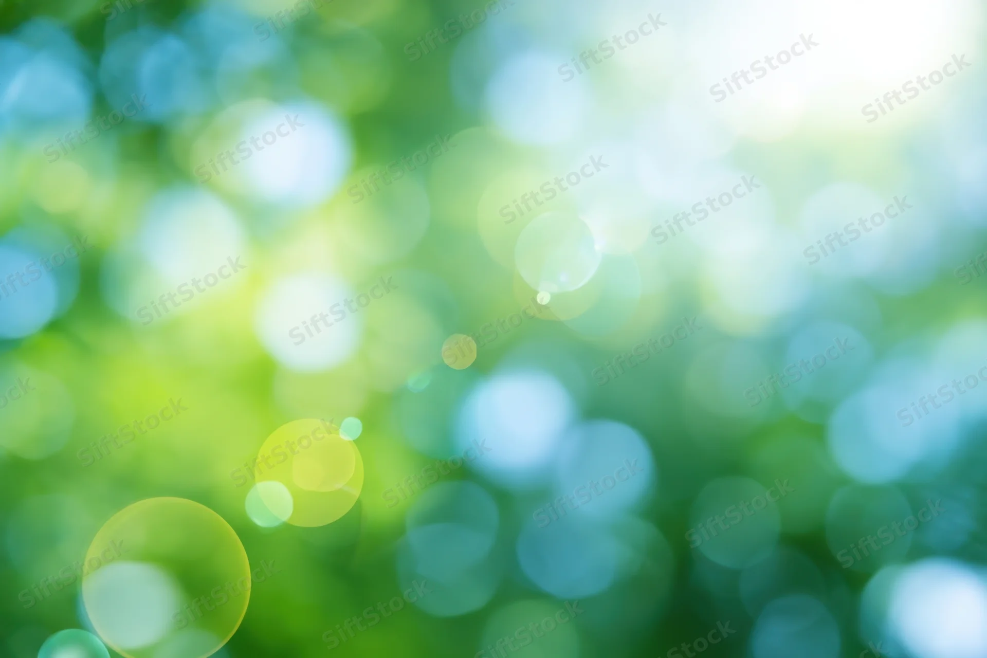 Abstract nature background with soft green and blue bokeh from sunlight filtering through foliage