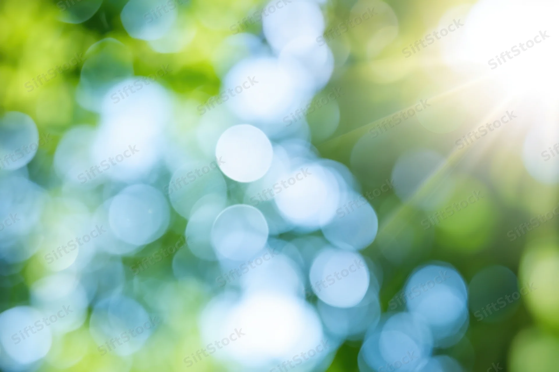 Sunlit abstract nature background with soft green and blue bokeh