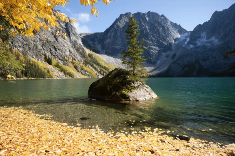 Autumn lake surrounded by mountains with golden leaves on shore and rock in water