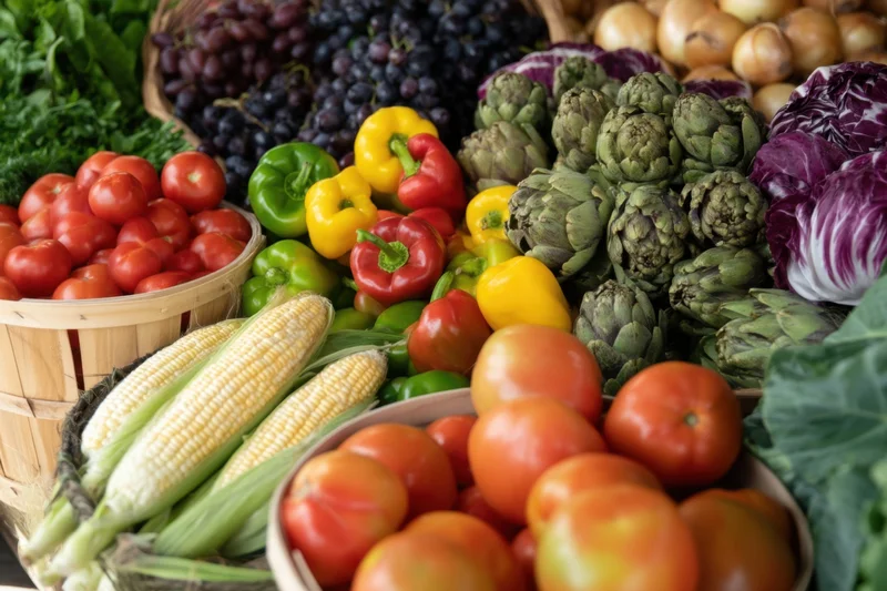 Colorful assortment of fresh vegetables and fruits arranged in baskets and bowls at a market display