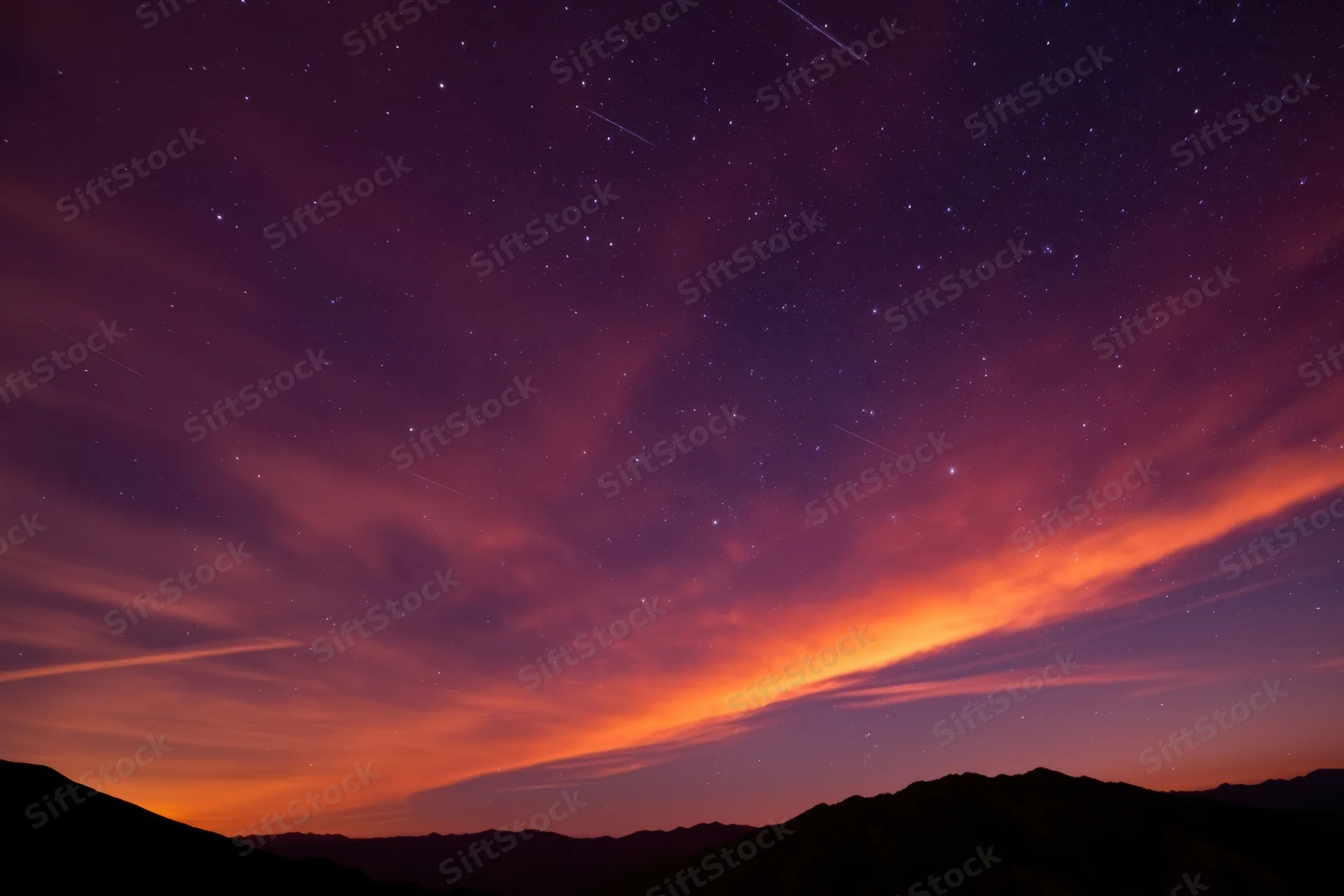 Starry night sky with glowing nebula above mountain silhouette