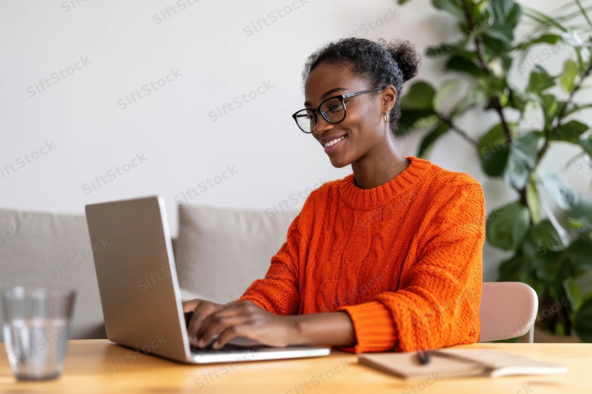 Woman typing on laptop at wooden table in home office setting