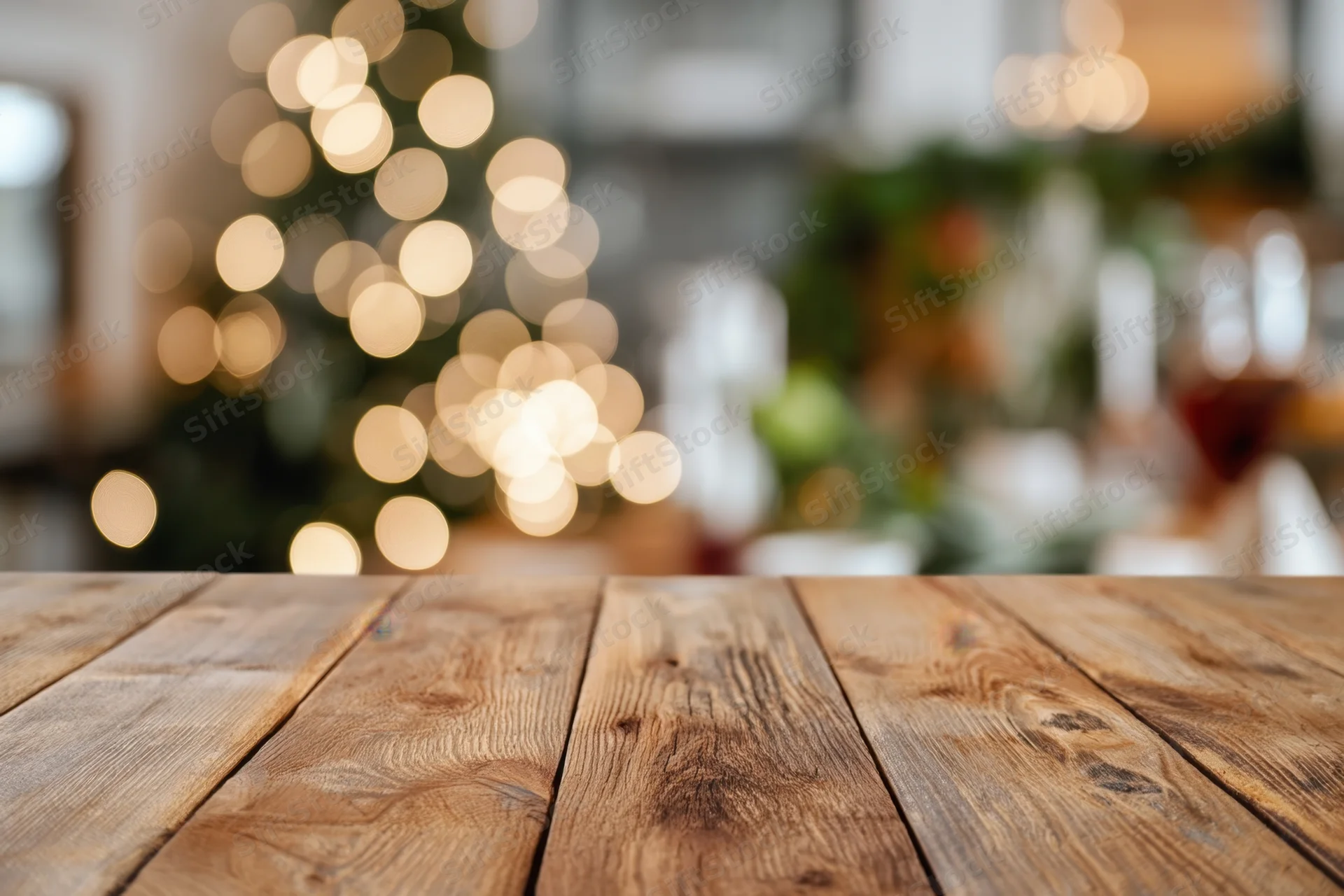 Wooden table surface in foreground with blurred christmas tree lights in background