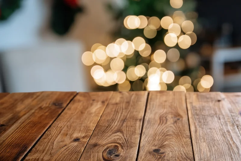 Wooden table in foreground with blurred christmas lights in background