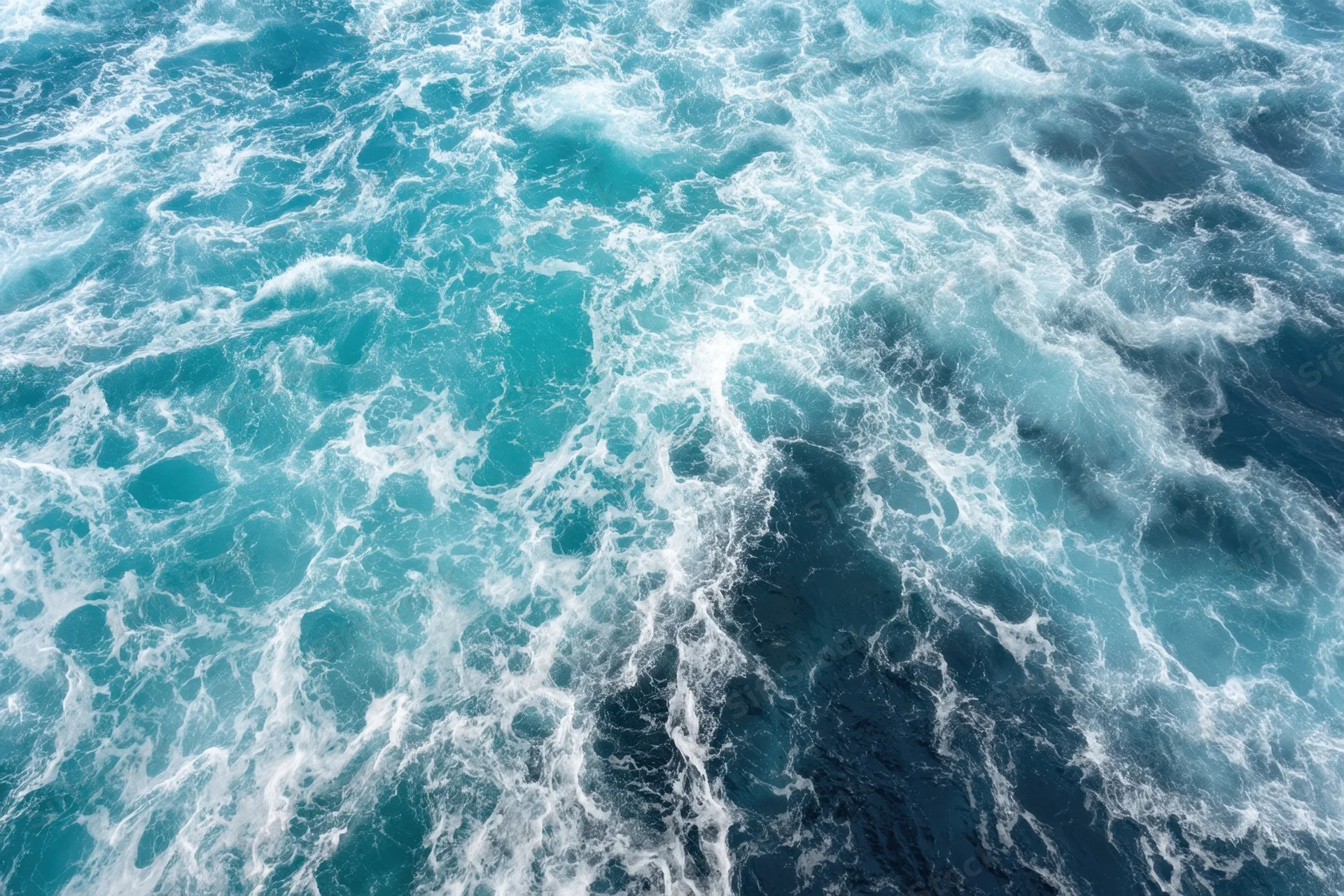 Swirling turquoise ocean waves with white foam from an aerial view