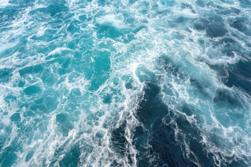 Swirling turquoise ocean waves with white foam from an aerial view