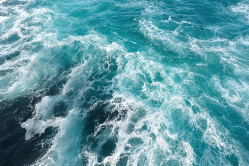Swirling turquoise ocean waves with white foam from an aerial view