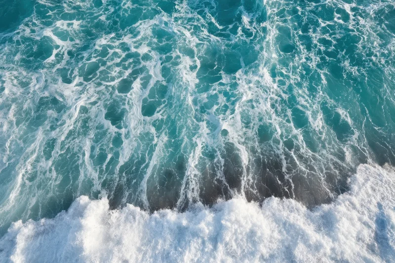 Aerial view of turquoise ocean waves with white foam swirling across the surface