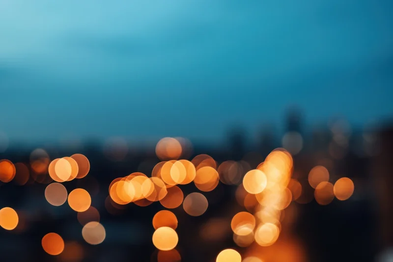 Blurred city lights forming warm orange and yellow bokeh against a twilight sky