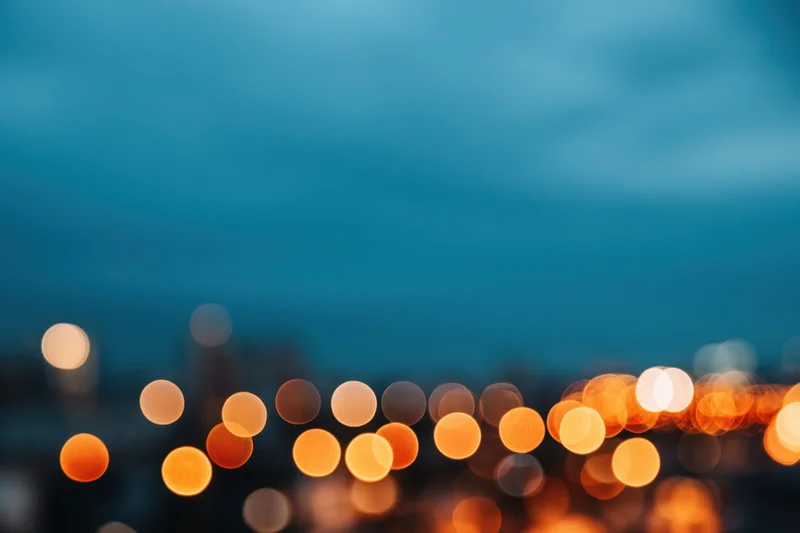 Blurred city lights forming warm orange and yellow bokeh against a blue twilight sky
