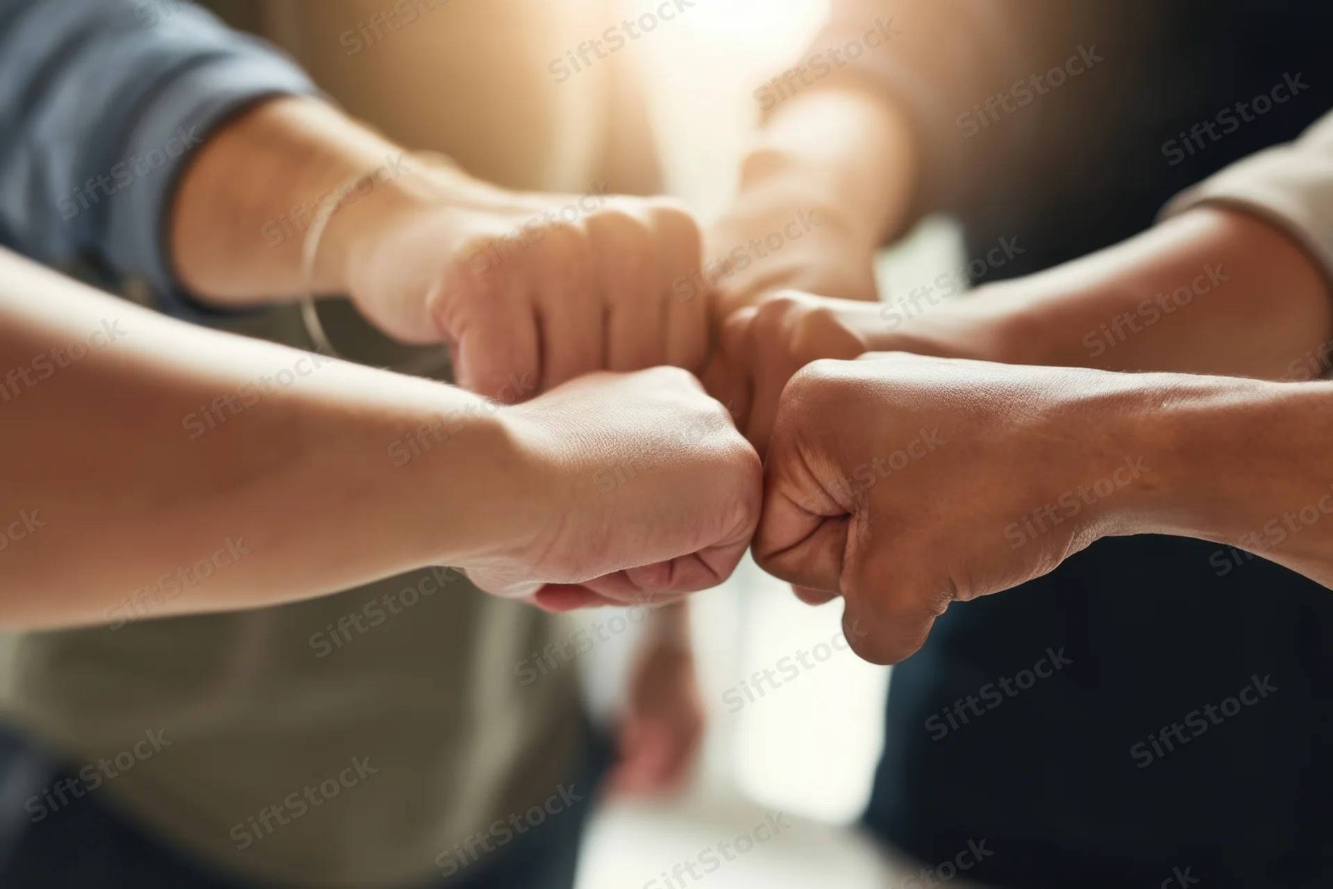 Multiple hands joining in a fist bump gesture indoors