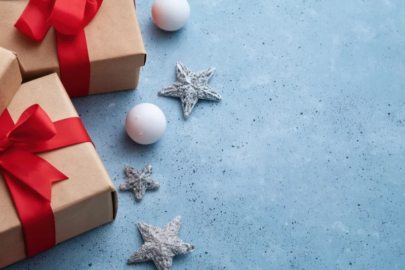 Wrapped gifts with red ribbons and silver stars on a blue speckled surface