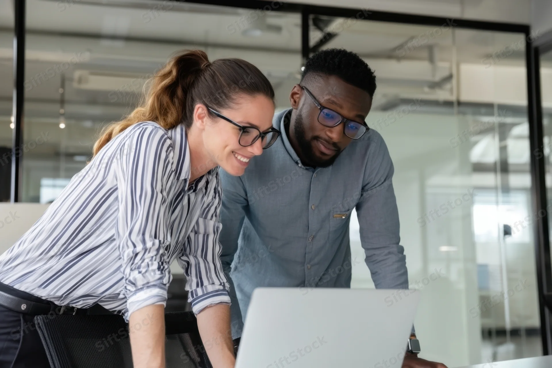 Woman and man collaborating on laptop in modern office space