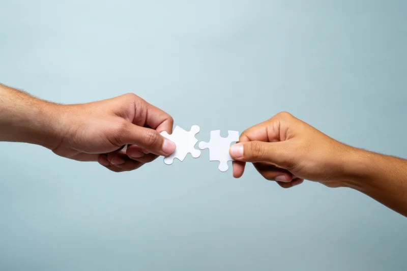 Two hands connecting white puzzle pieces against a soft blue background