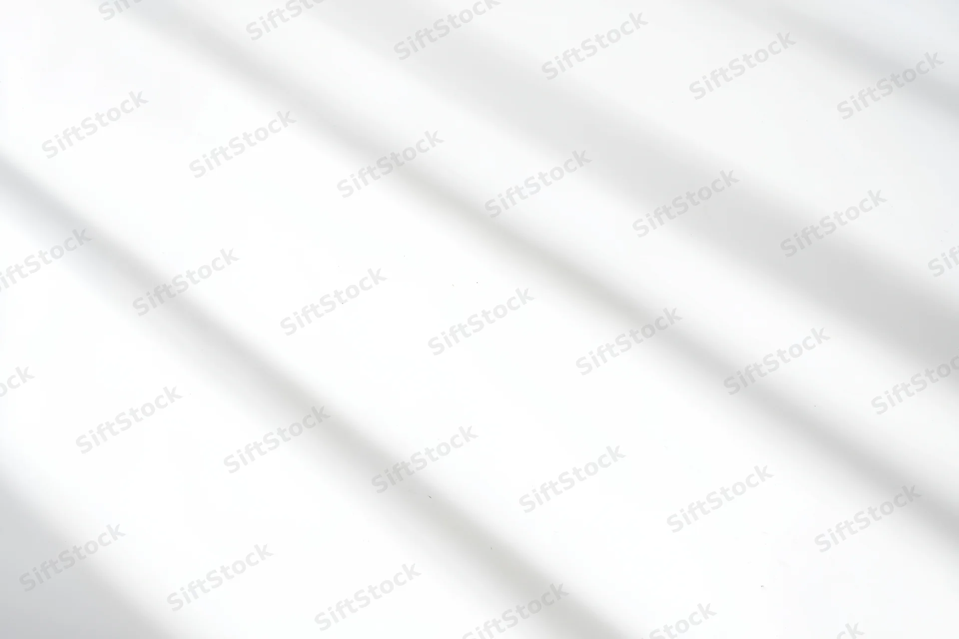 Diagonal light and shadow on a white surface creating a minimalist abstract background