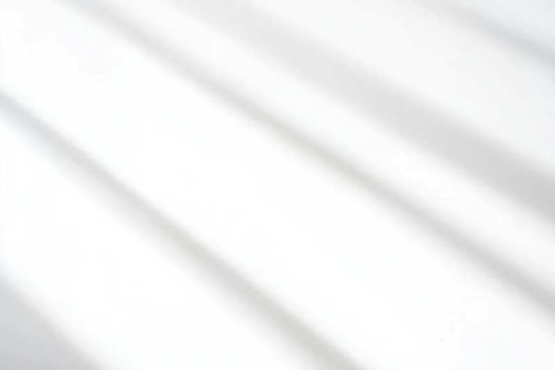 Diagonal light and shadow on a white surface creating a minimalist abstract background