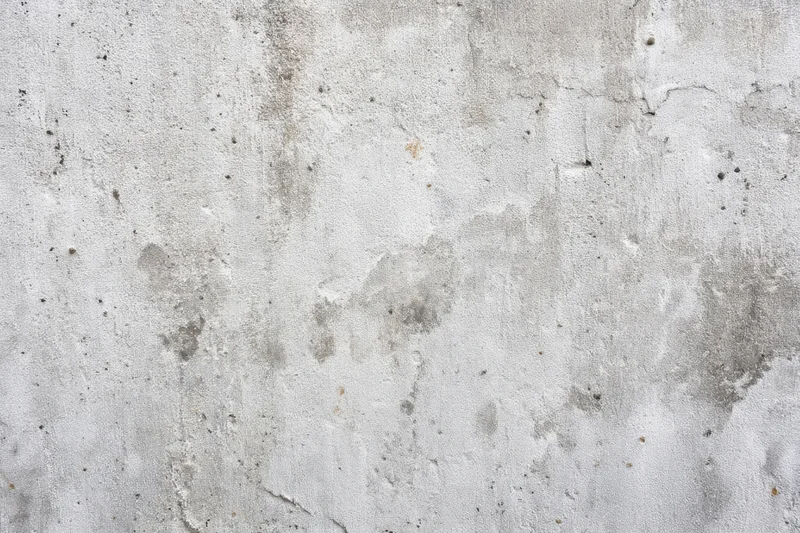 Close-up of a weathered light gray concrete wall with cracks and stains