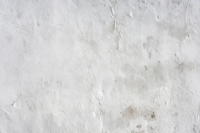 Close-up of a weathered light gray concrete wall with cracks and surface imperfections