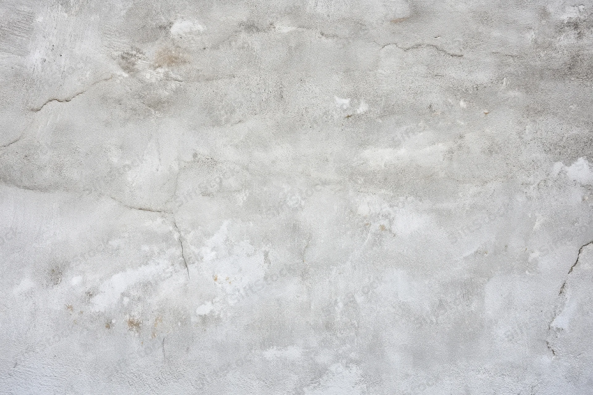 Close-up of a weathered light gray concrete wall with cracks and peeling surface