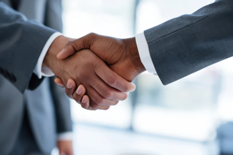 Two men in suits shaking hands in an office setting