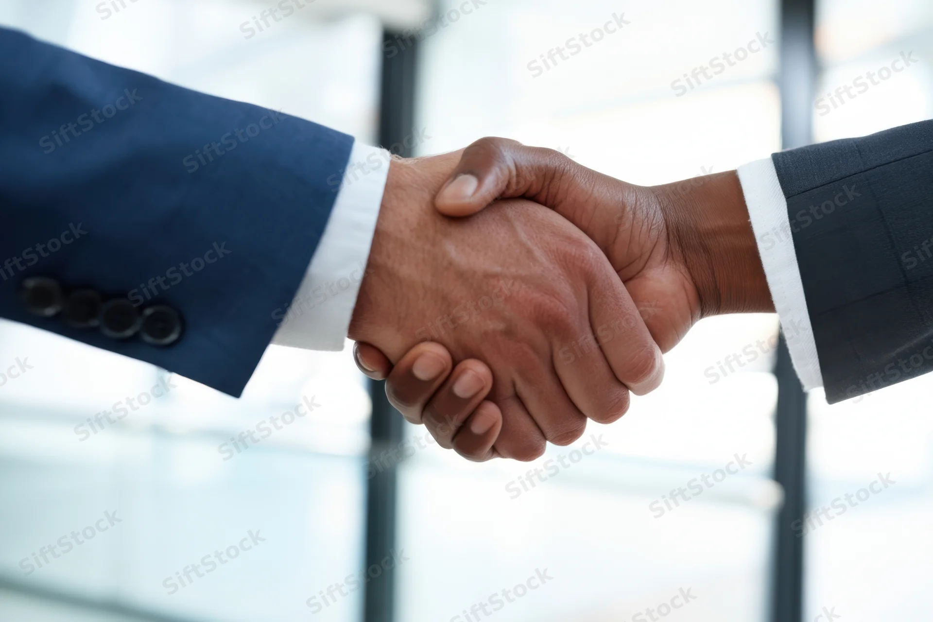 Two men in suits shaking hands in an office interior