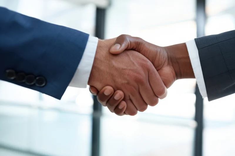 Two men in suits shaking hands in an office interior