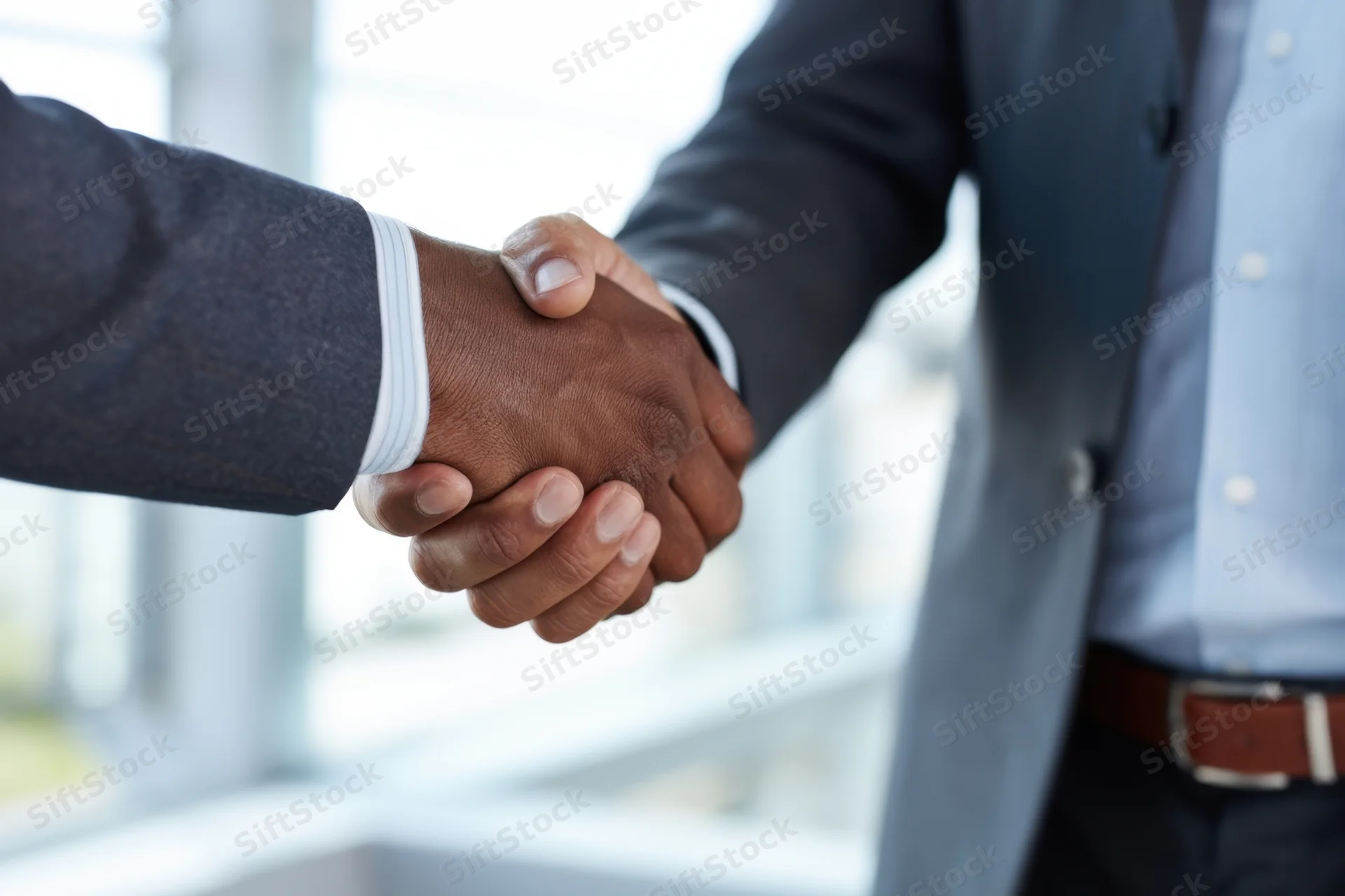 Two men in suits shaking hands in an office setting