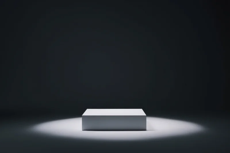 White rectangular pedestal centered under spotlight on dark stage