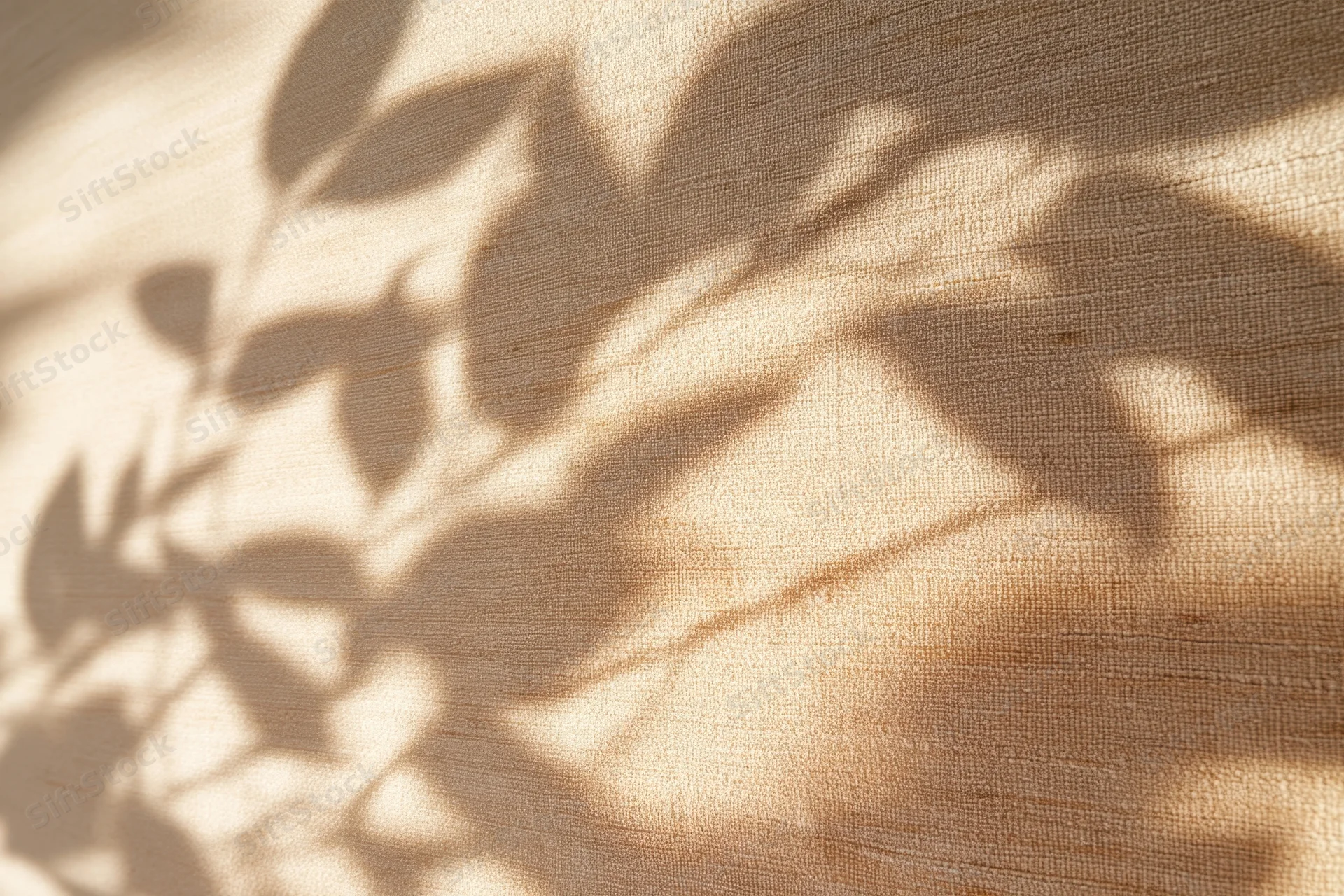 Dappled leaf shadows on beige fabric surface