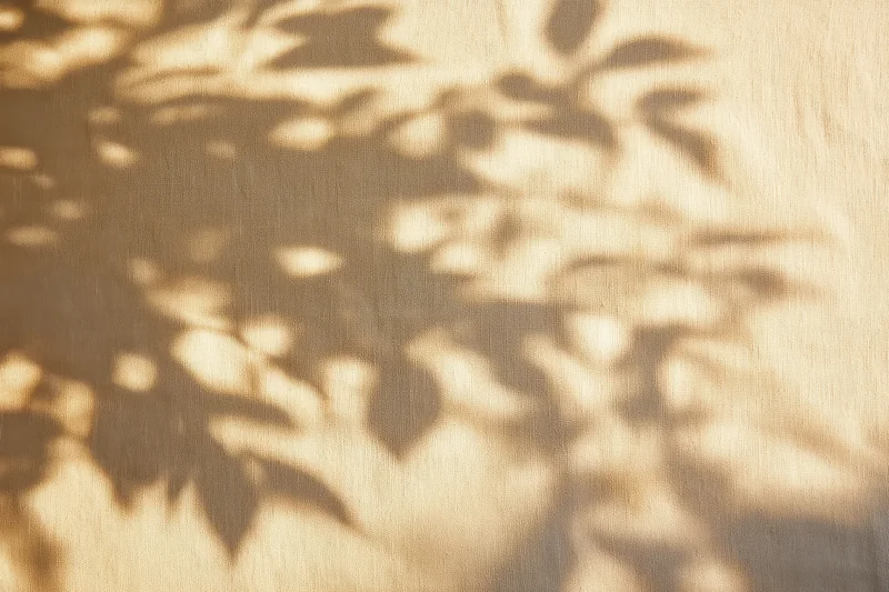 Dappled leaf shadows on beige fabric texture