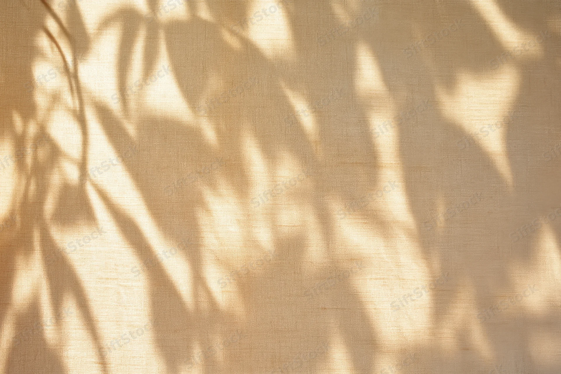 Dappled leaf shadows on beige fabric texture