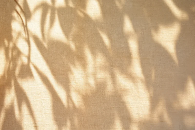 Dappled leaf shadows on beige fabric texture
